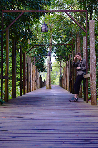 A tourist leaning against one of Sukau Rainforest Lodge walkways pole